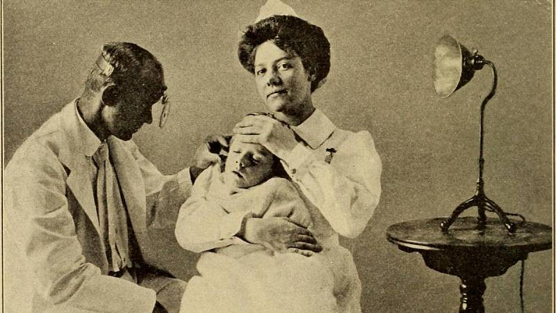 Vyšetření ucha dítěte. Dětské nemoci z roku 1910.  Koplik, Henry, 1858- (ze starého katalogu)